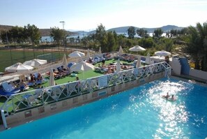 Alberca al aire libre, sombrillas en la alberca y camastros