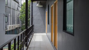 A narrow corridor with a tiled floor, a black railing, and a grey brick wall. - Varinda Hostel (Bangkok)