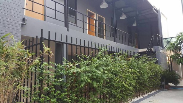 A modern building with a grey facade, multiple windows, and a balcony with a metal railing. - Varinda Hostel (Bangkok)