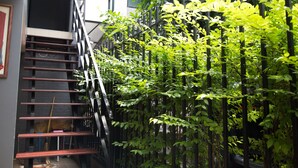 A staircase with metal railings and a view of a building with a black exterior and glass windows. - Varinda Hostel (Bangkok)