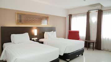 Une chambre d’hôtel avec deux lits, une chaise rouge, une petite table et un élément décoratif mural.
