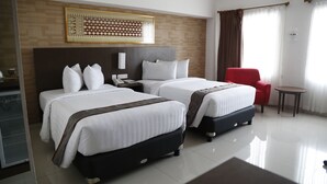 Une chambre d’hôtel avec deux lits, une chaise rouge, une petite table et un élément décoratif mural.