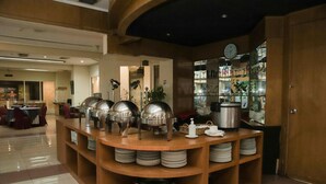 Un buffet avec plusieurs points de service, une horloge au mur et une grande variété de plats et d’ustensiles.