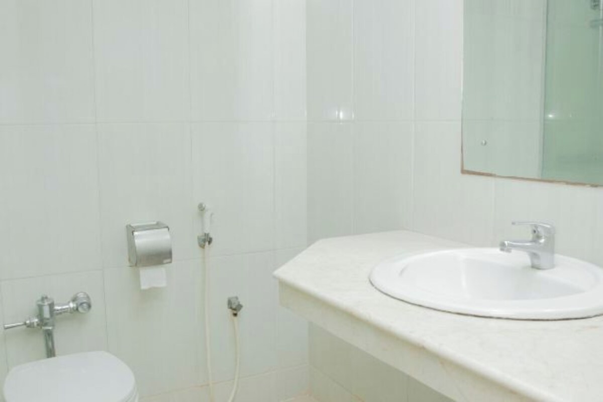 Un baño con lavamanos blanco, inodoro y dispensador de toallas de papel.