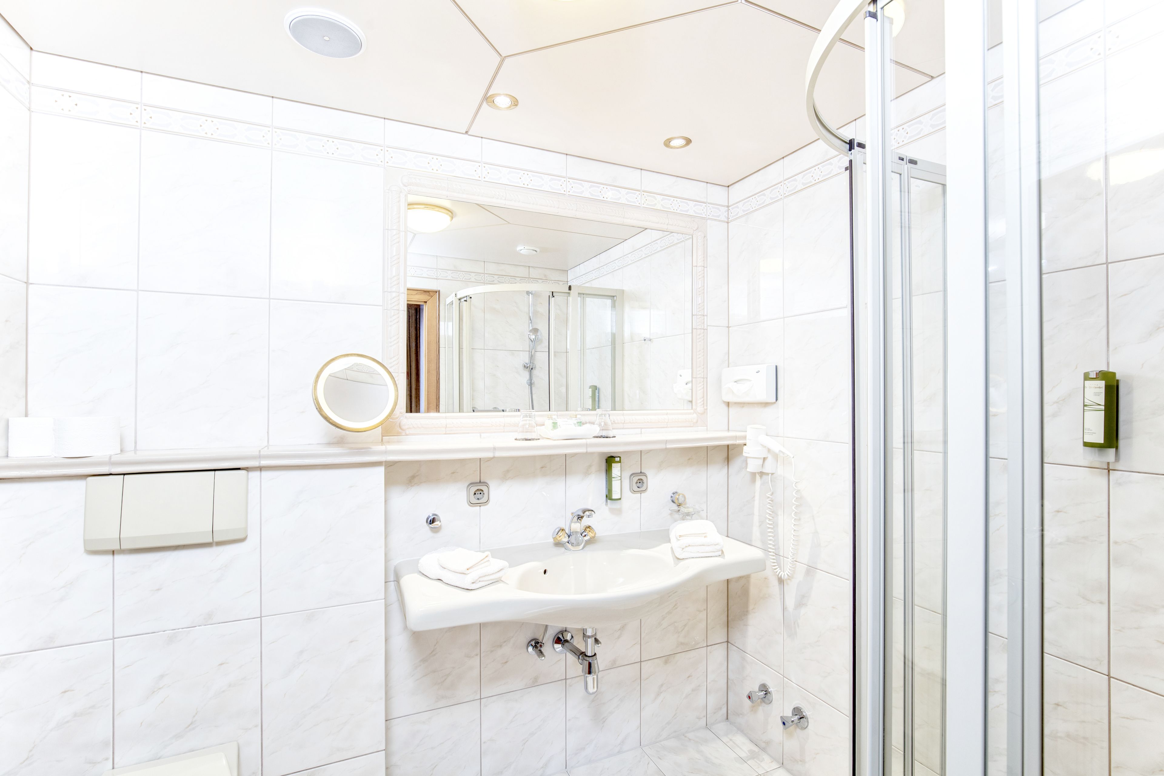 A modern bathroom with a glass-enclosed shower, a large mirror, and a vanity with a sink and towel rack.