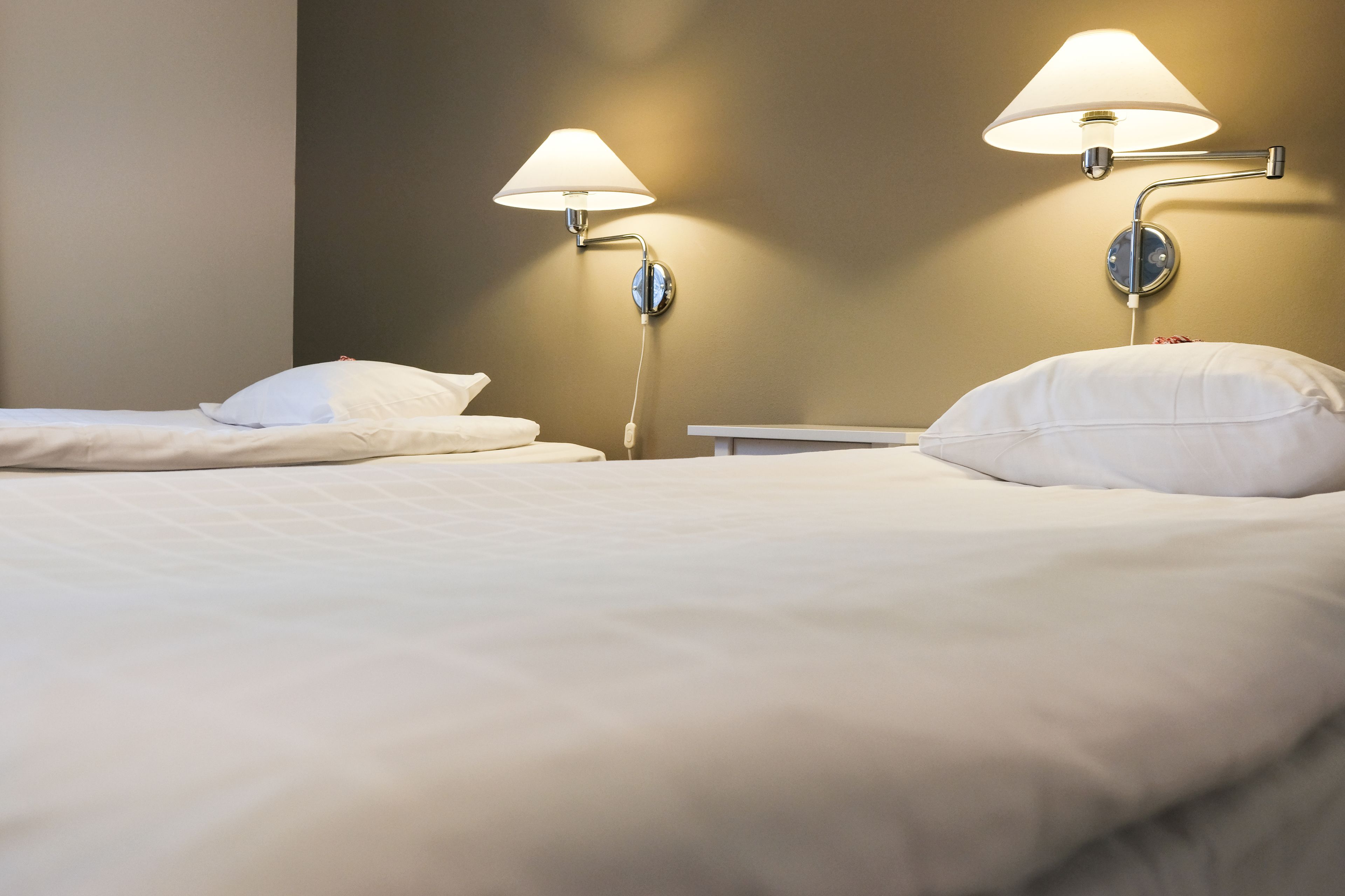 A hotel room with two bedside lamps, a bed with white bedding, and a nightstand.