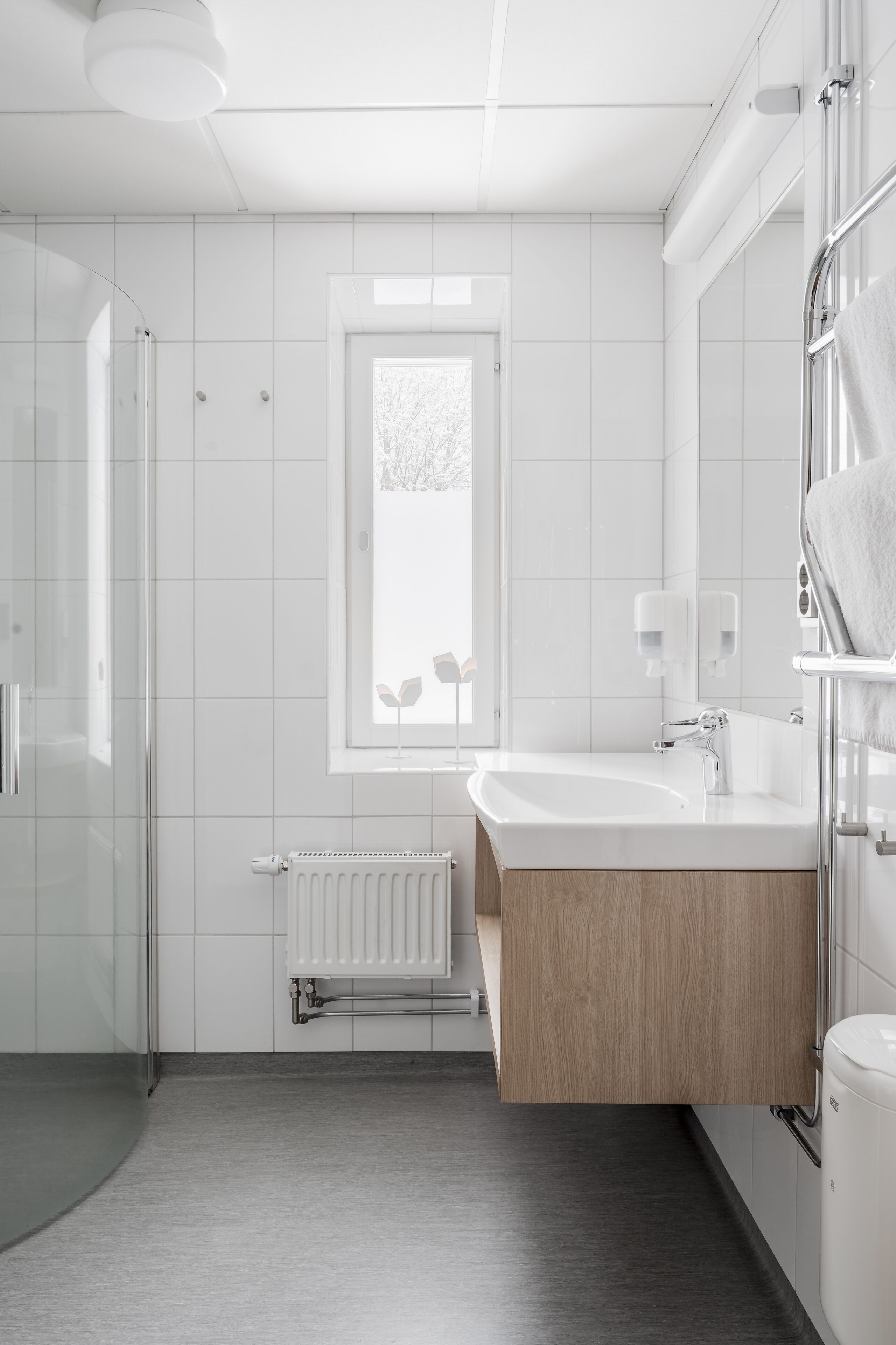 Ein modernes Badezimmer mit Duschkabine aus Glas, einem weißen Waschbecken mit Holzschrank und einem großen Spiegel.