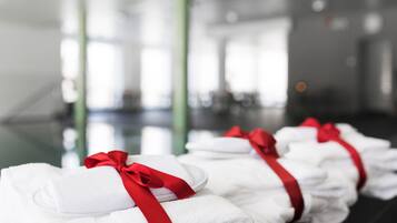 Neatly folded white towels with red ribbons, arranged in a row on a reflective surface in a well-lit indoor space.