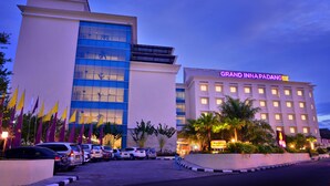 A hotel with multiple floors, a prominent sign, and a parking lot with several cars. - Truntum Padang (Padang)
