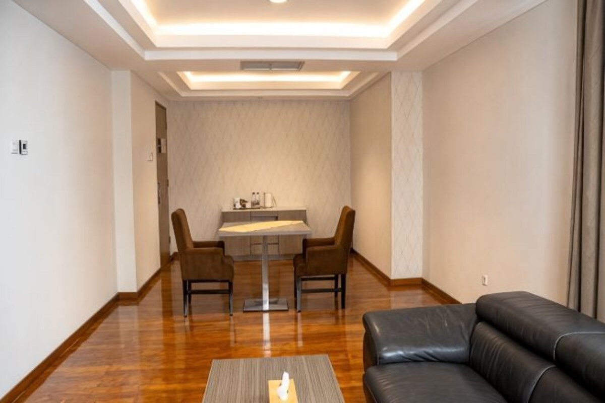 A modern living room with a leather sofa, a dining table with chairs, and a wooden floor.