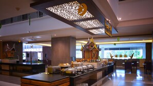 A modern hotel lobby with a buffet area, a reception desk, and a decorative architectural feature. - Truntum Padang (Padang)