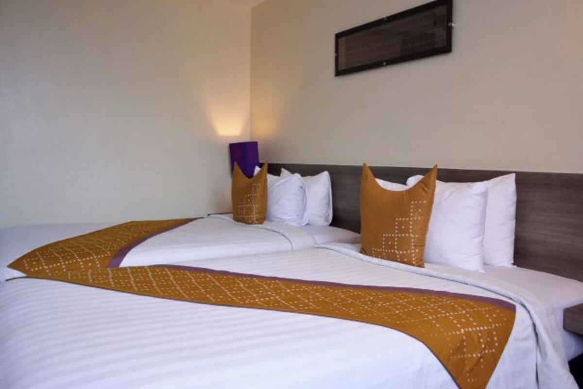 A hotel room with a large bed, two pillows, and a headboard.