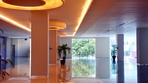 A spacious lobby with a high ceiling, large windows, and a central water feature. - Truntum Padang (Padang)