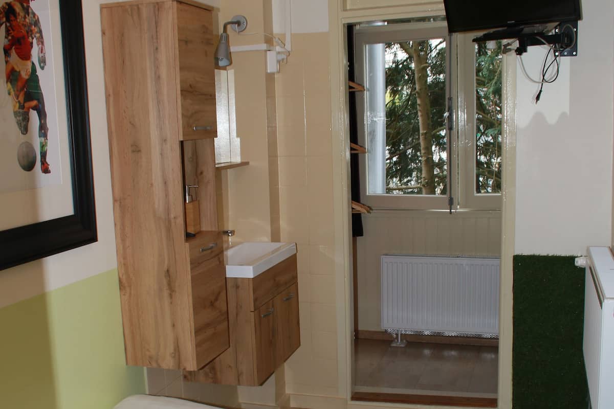 A bedroom with a bed, wooden cabinets, a window, and a television.