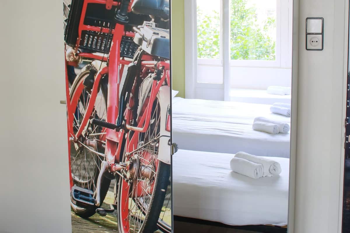 A room with a bed, a bicycle, and a chandelier.