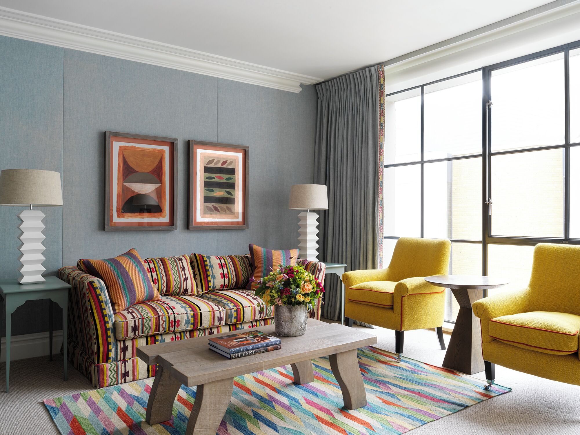 A modern living room with a sofa, armchairs, a coffee table, and artwork on the wall.