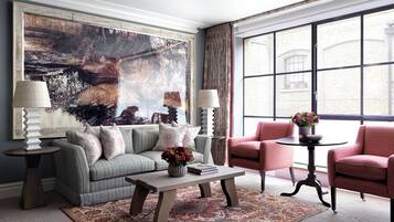 A living room with a large painting, a sofa, a chair, a coffee table, and a rug.