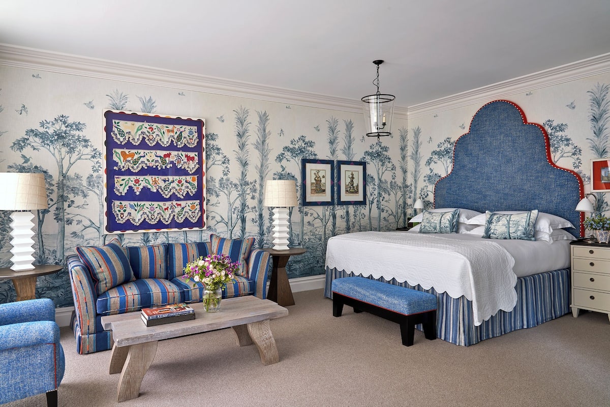 A bedroom with a large bed, a sofa, a coffee table, and a wall tapestry.