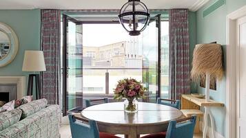 A dining area with a round table, blue chairs, and a vase of flowers.