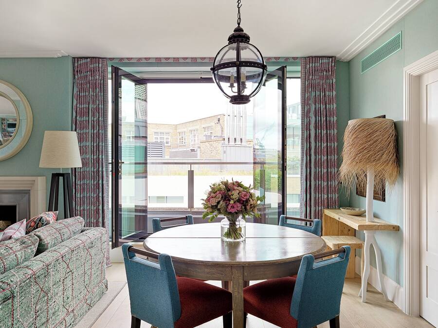 A dining area with a round table, blue chairs, and a vase of flowers.