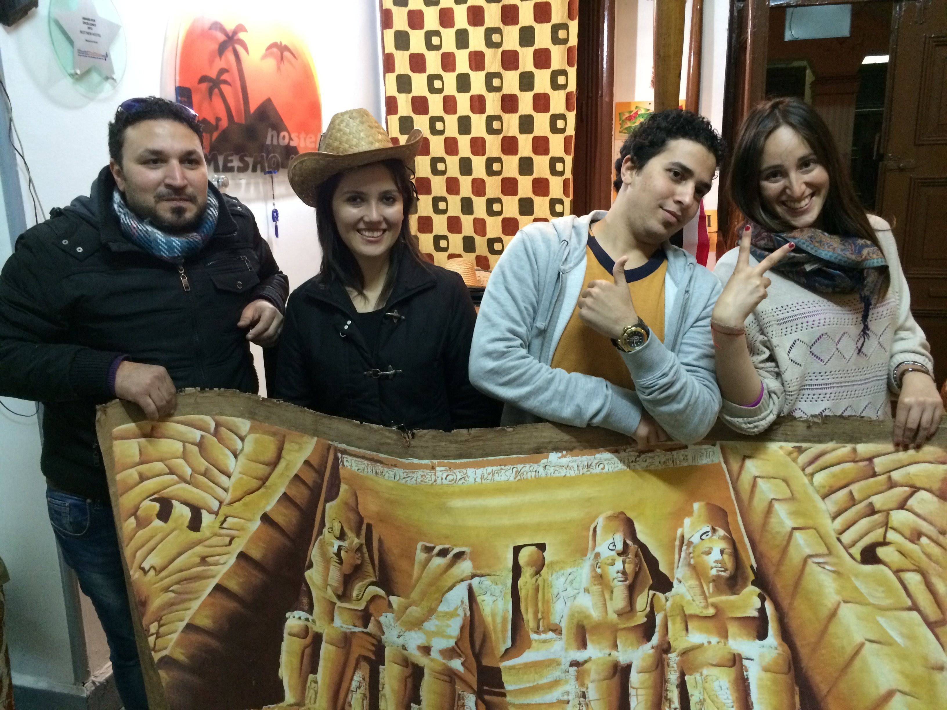 A group of people standing in front of a wall with a mural depicting ancient Egyptian figures.