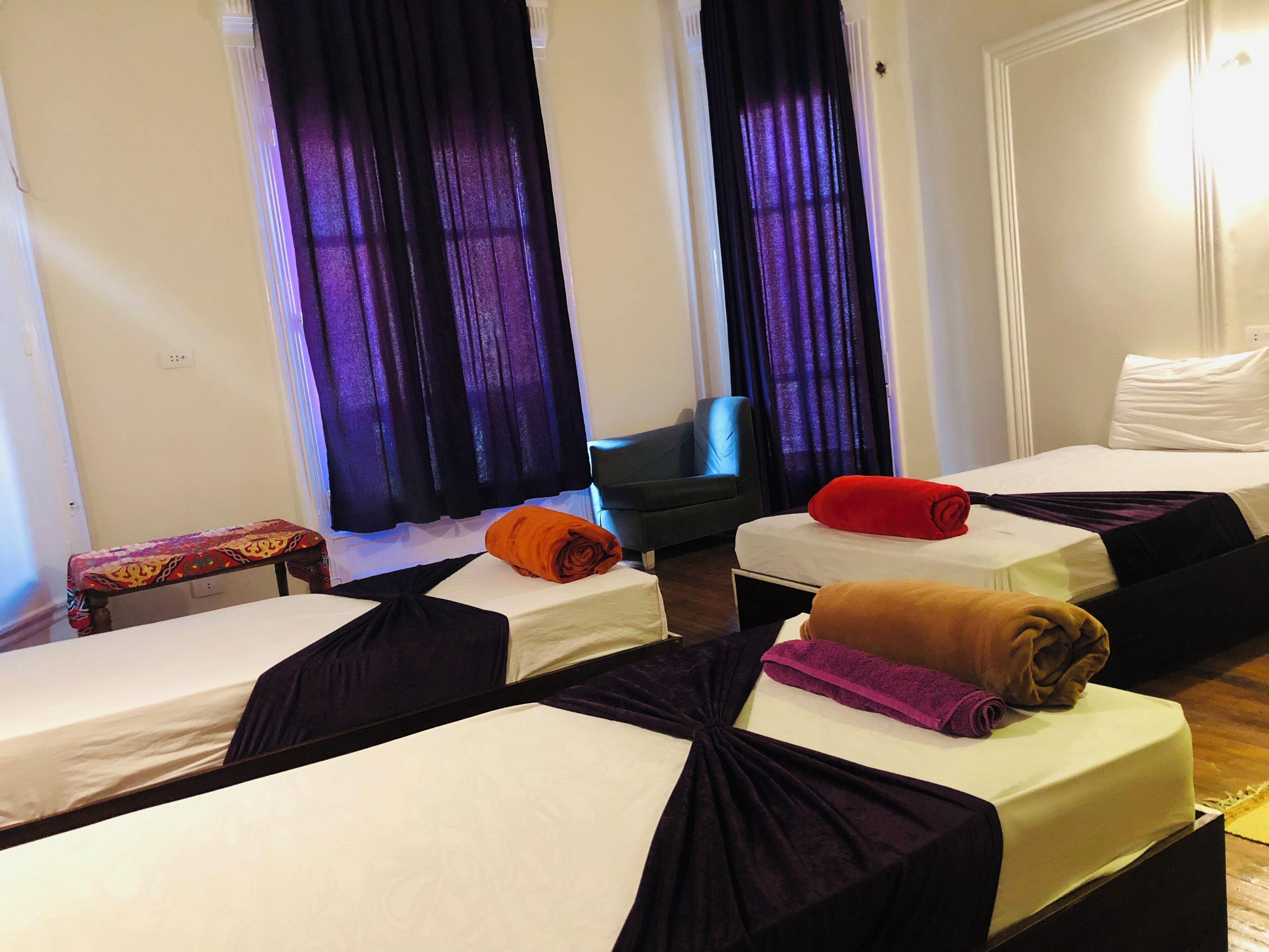 A hotel room with two beds, a small table, and a chair.