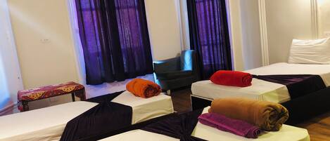 A hotel room with two beds, a small table, and a chair.