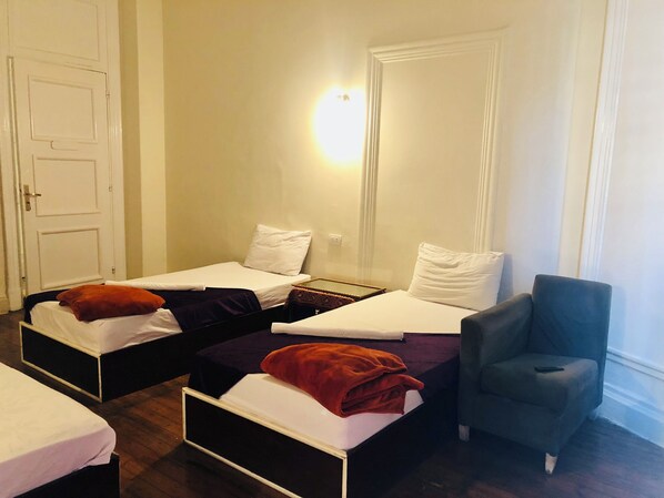A room with two beds, a chair, and a nightstand.