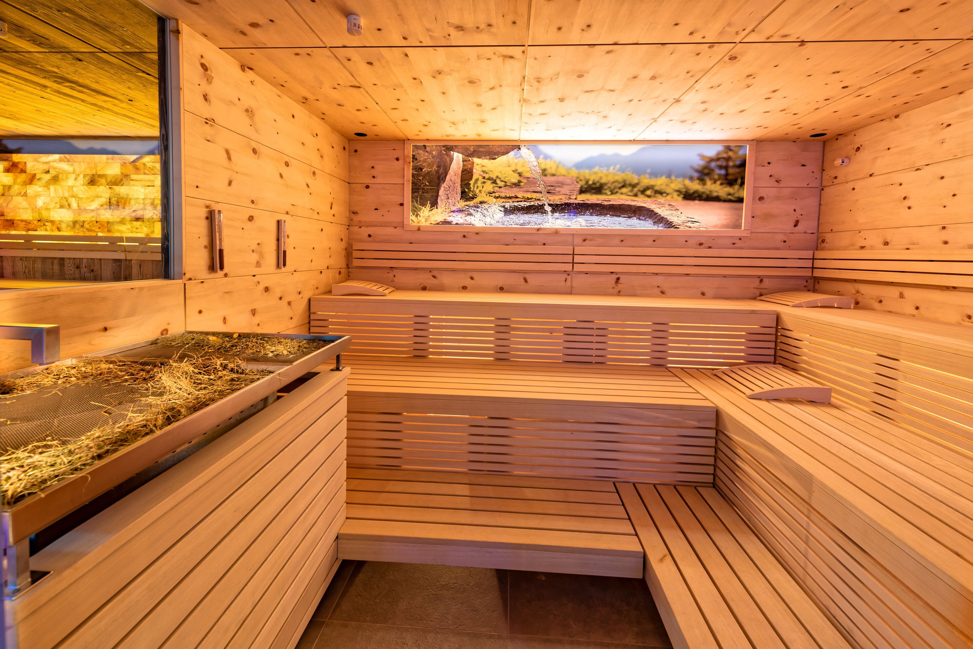 A wooden sauna with benches and a window overlooking a natural landscape.