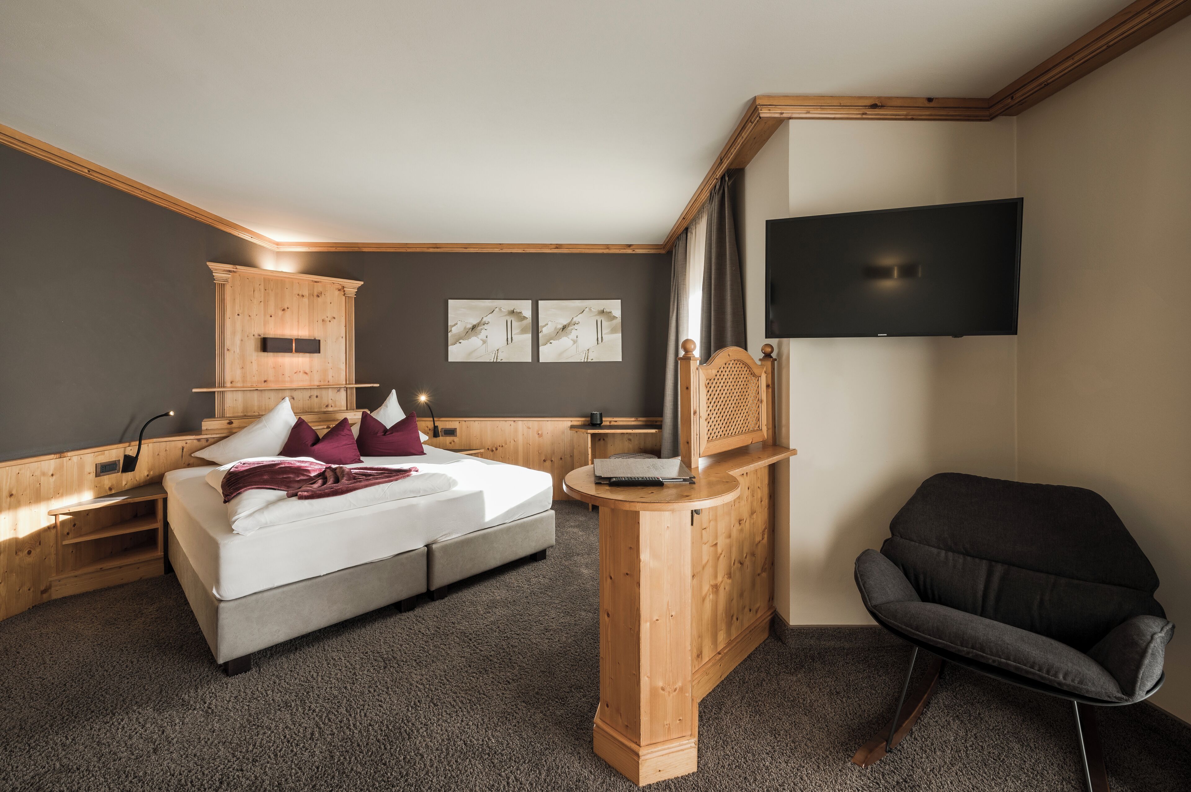 A bedroom with a bed, a wooden cabinet, a TV, and a chair.
