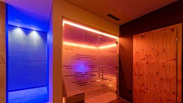Un baño moderno con separador de vidrio, puerta de madera y zona de ducha iluminada en azul.