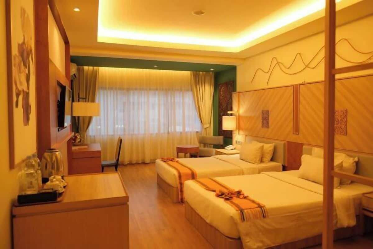 A hotel room with two beds, a desk, a chair, a small table, and a window with curtains.