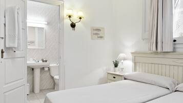 A bedroom with a bed, bedside table, lamp, and a view of the bathroom.