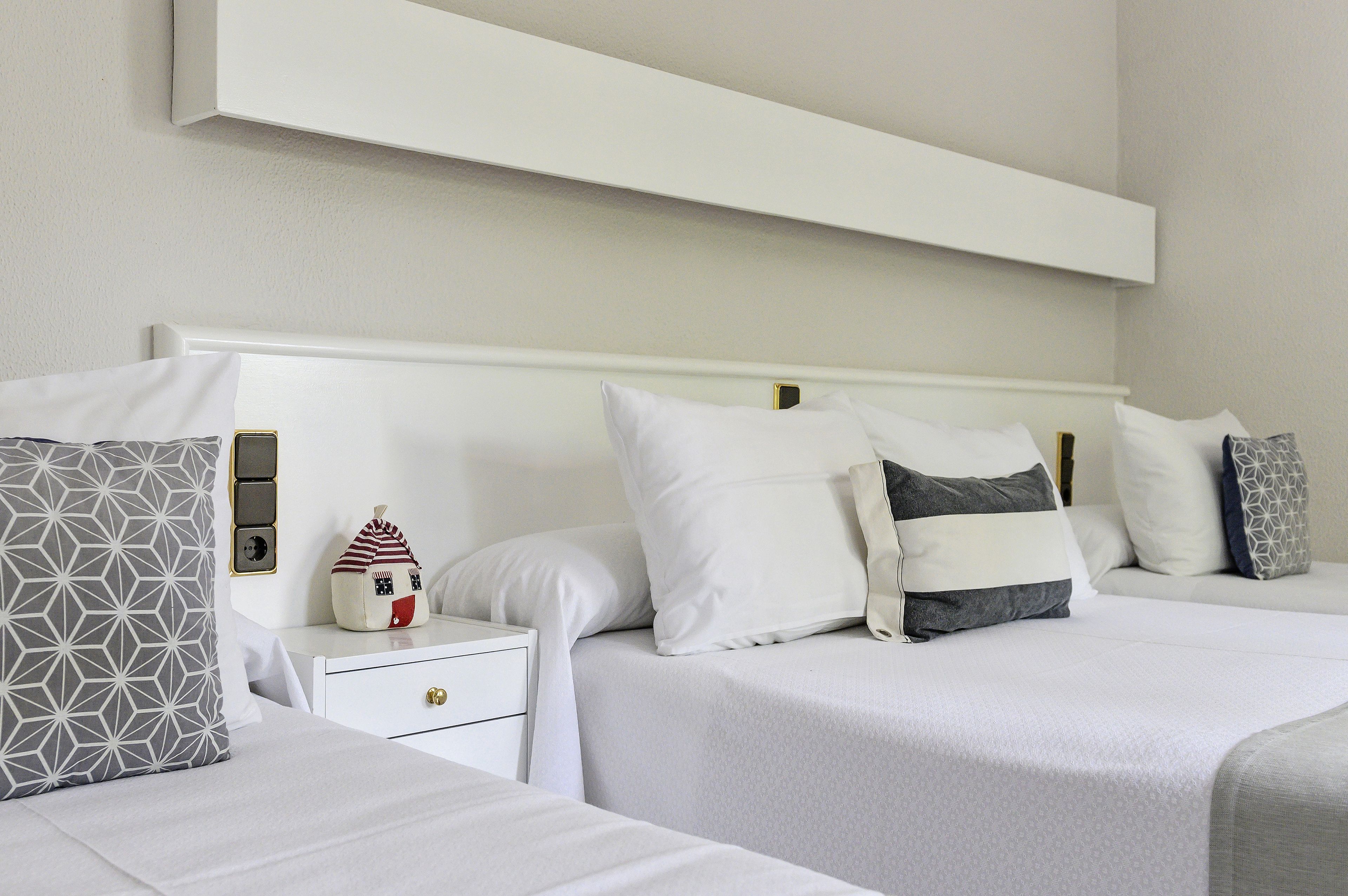 Una habitación de hotel con dos camas, una mesita de noche y una repisa en la pared.