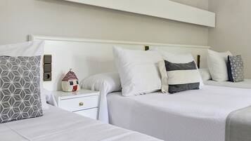 Una habitación de hotel con dos camas, una mesita de noche y una repisa en la pared.