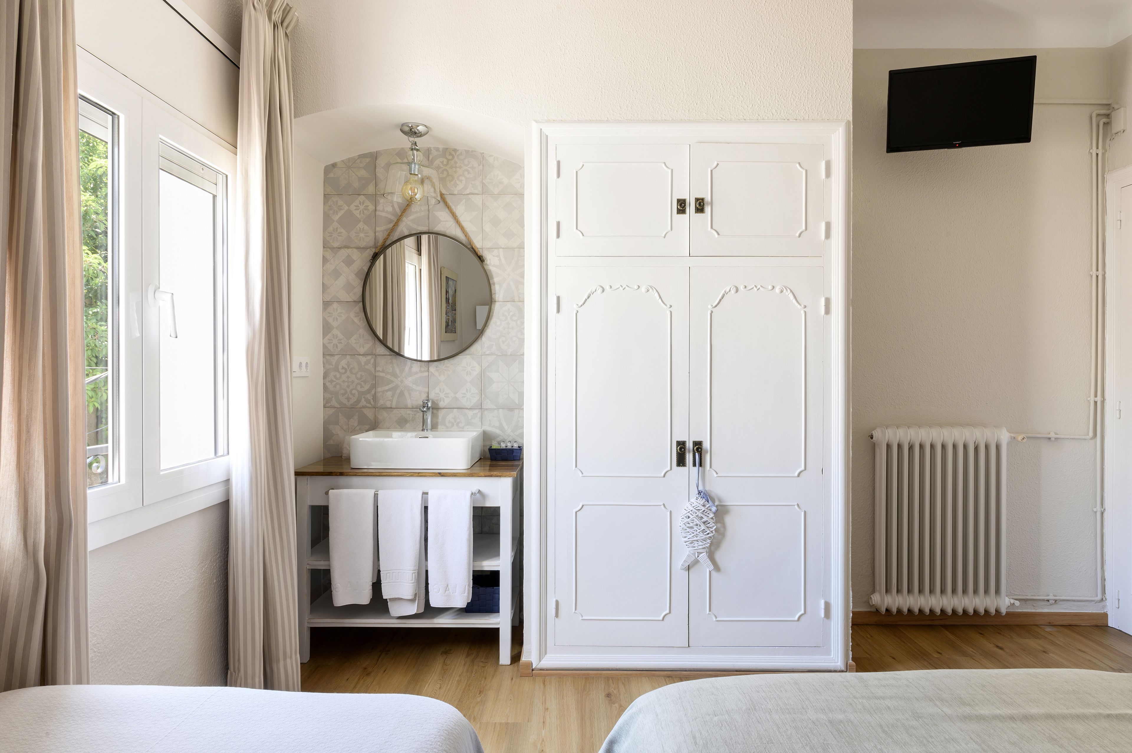 Una camera da letto con un letto, un armadio, uno specchio, un lavabo e un termosifone.