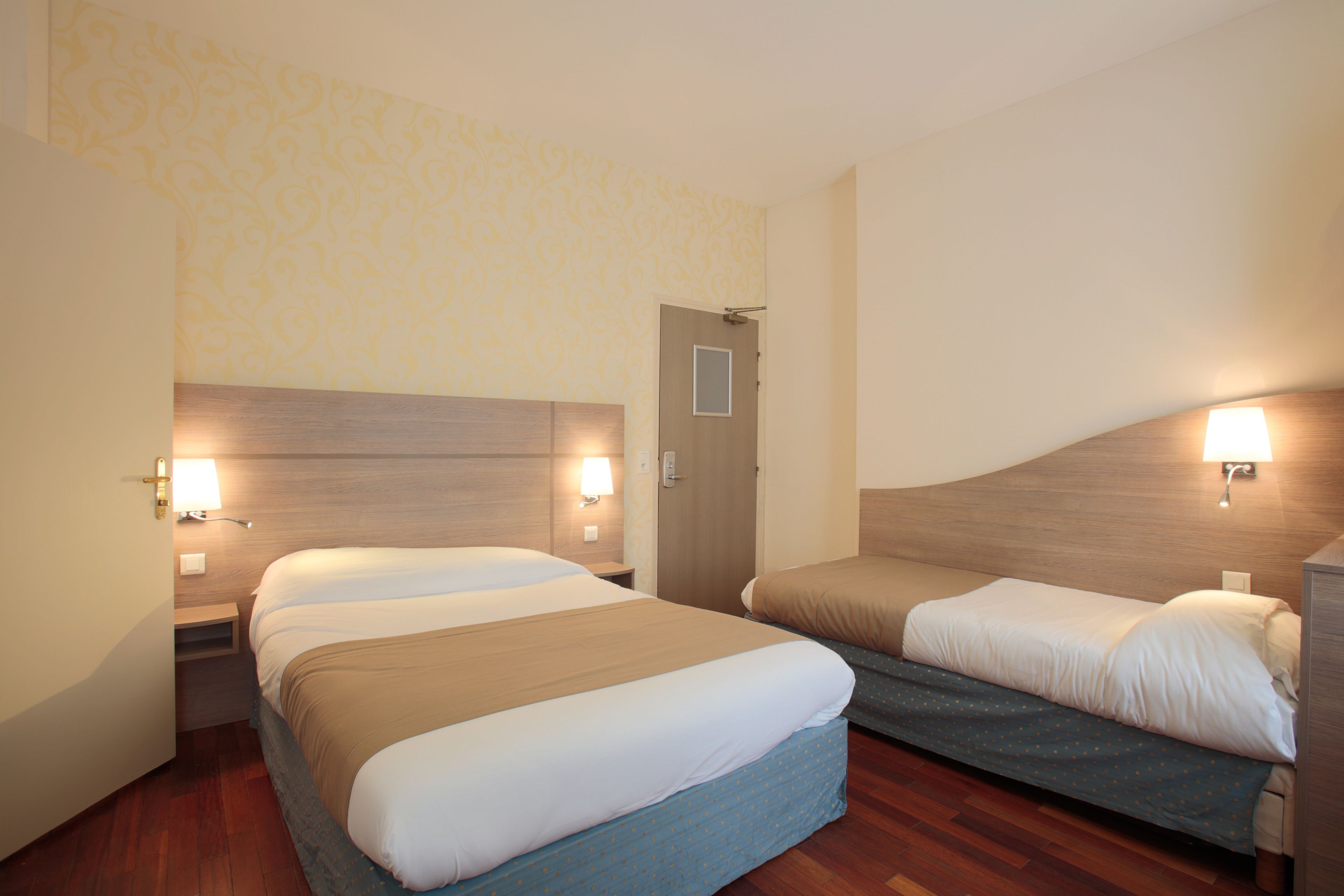 A hotel room with two beds, wooden headboards, and bedside lamps.