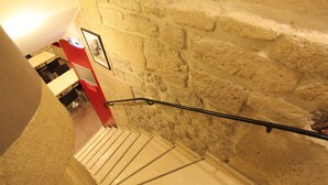 A staircase with a handrail, a wall with a rough texture, and a framed picture on the wall. - Grand Hôtel du Loiret (Paris)