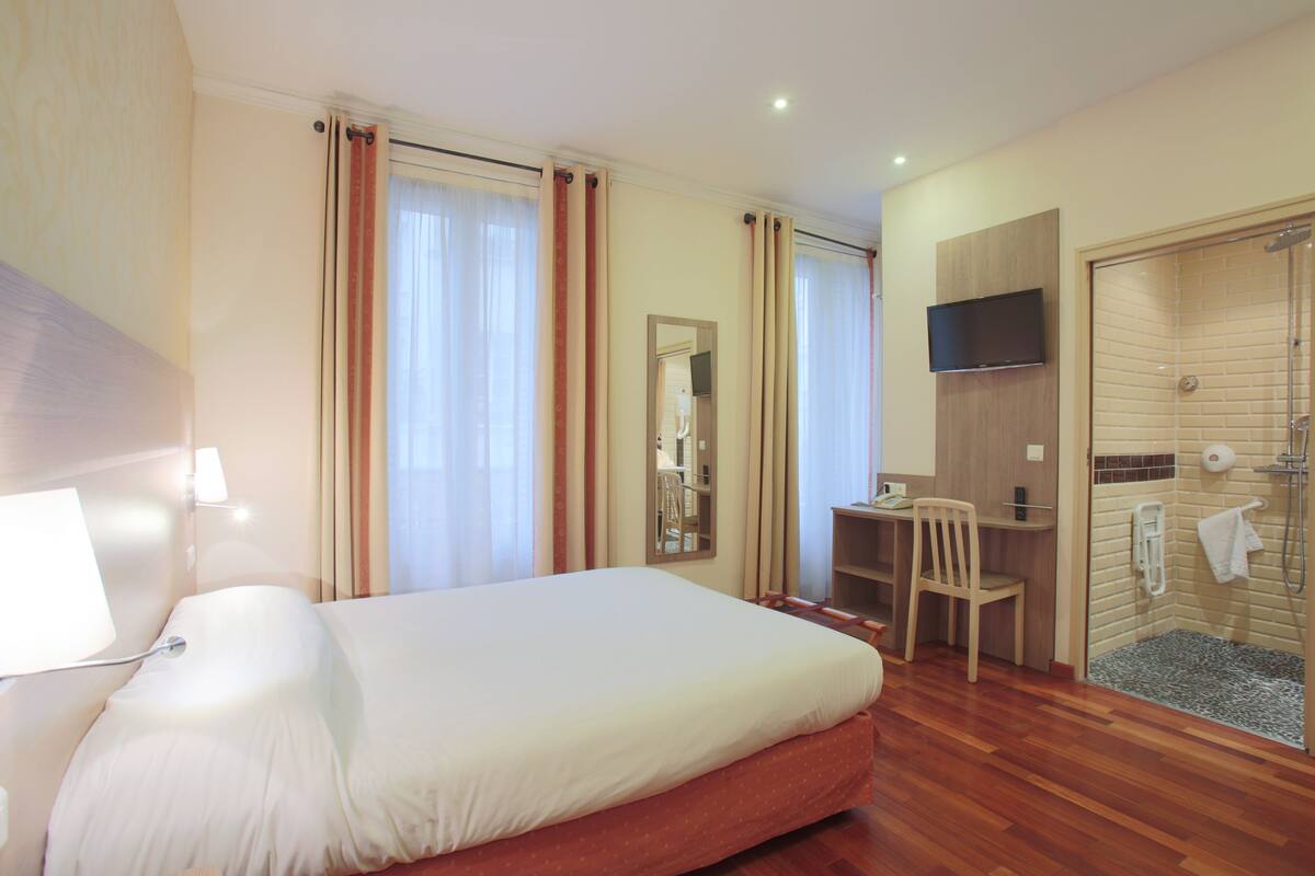 Ein Hotelzimmer mit Bett, Schreibtisch, Stuhl und einer Duschkabine.
