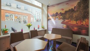 A restaurant with a view of a river and a bridge, featuring tables and chairs, and a window with a view of a building across the street. - Grand Hôtel du Loiret (Paris)