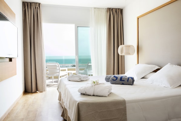 A hotel room with a bed, a TV, a balcony with a view of the sea, and a lamp. - R2 Buganvilla Hotel & SPA (Pajara)