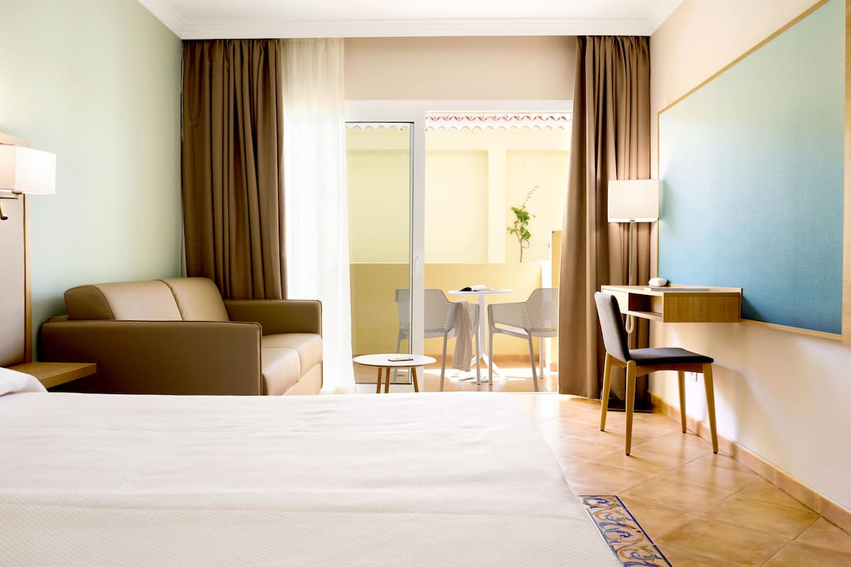 Una habitación de hotel con cama, escritorio, silla y una mesita.