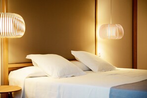 A neatly made bed with white linens and pillows, two hanging pendant lights, and a wooden headboard. - R2 Buganvilla Hotel & SPA (Pajara)