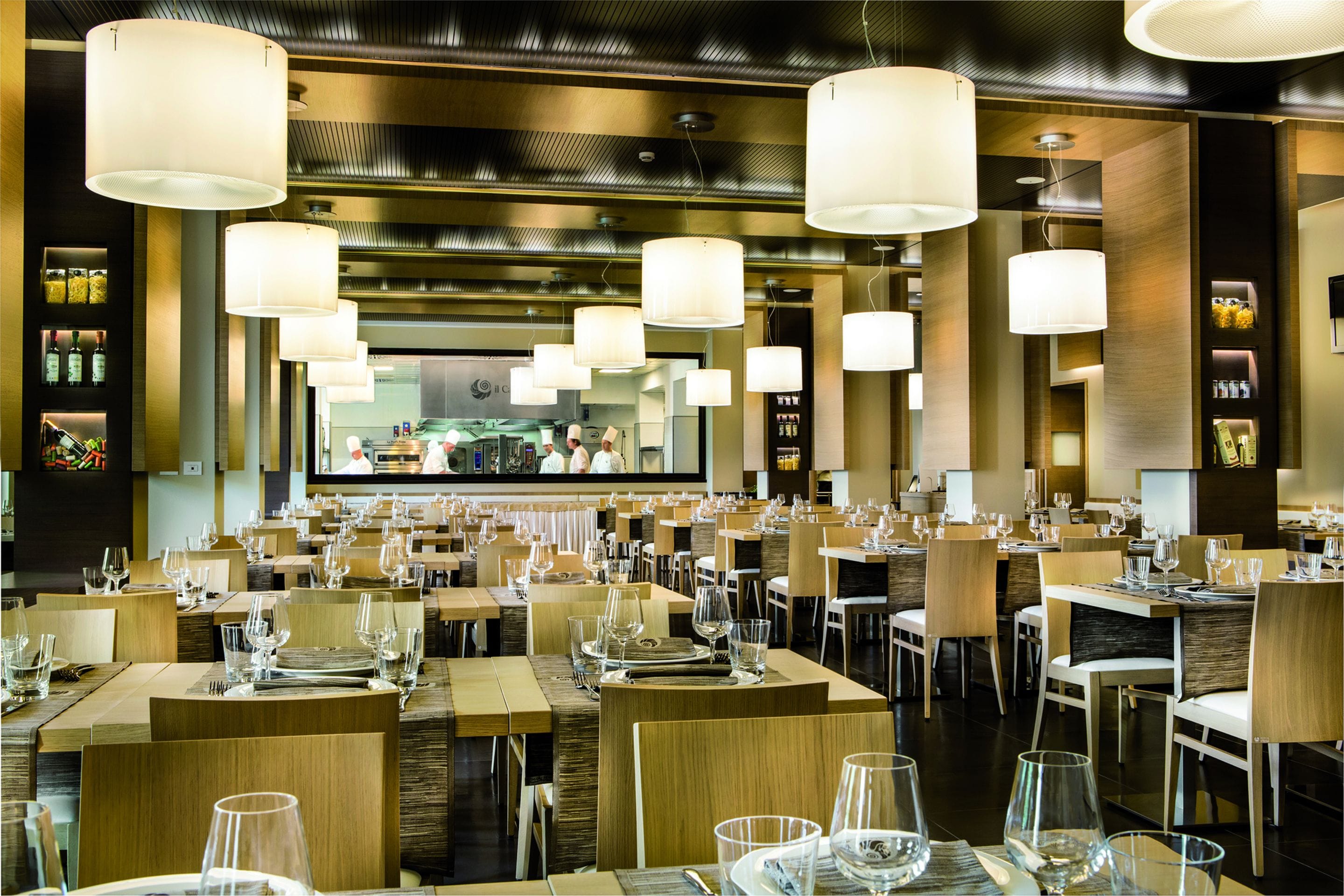Un ristorante con diversi tavoli, sedie e lampade a sospensione.