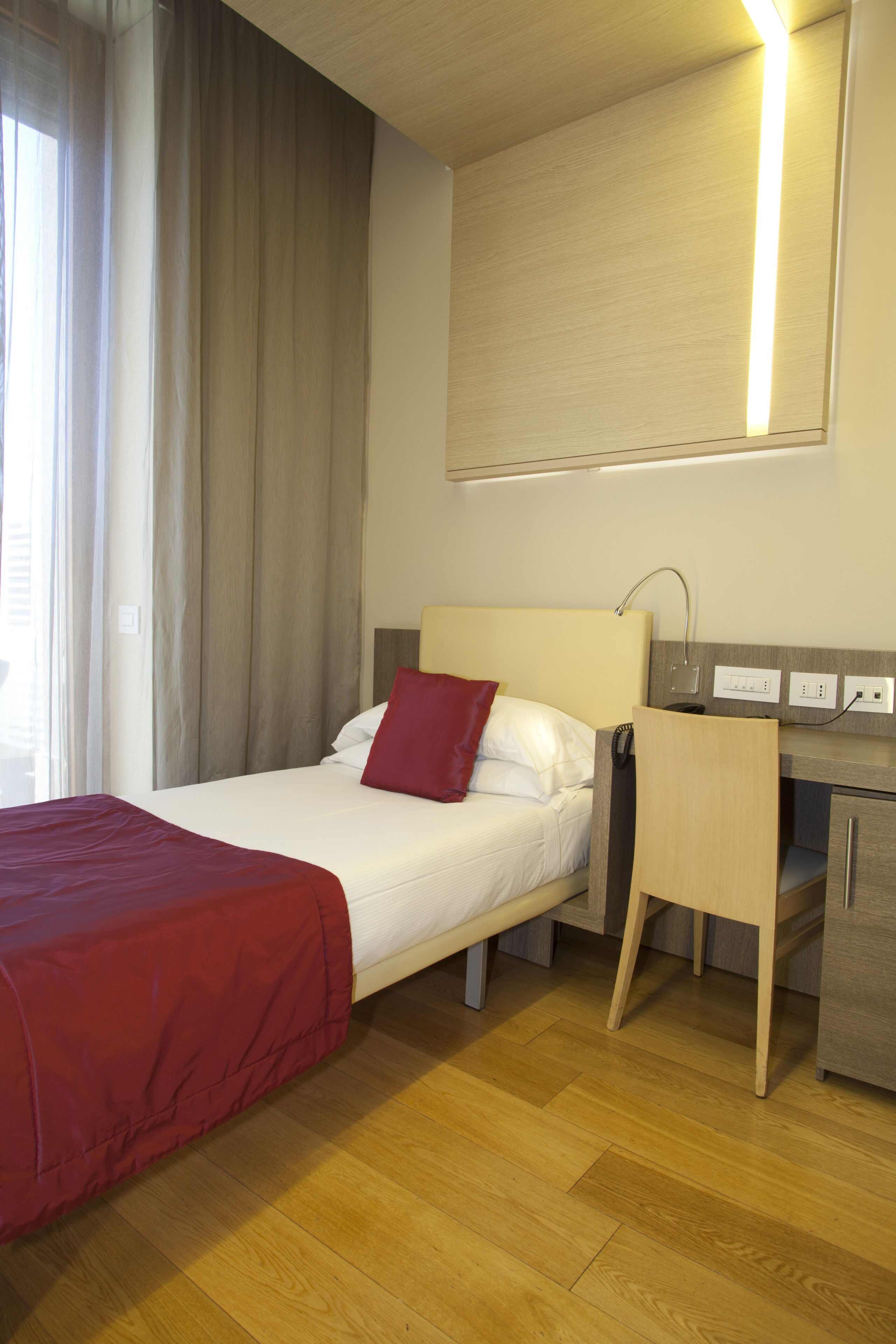 A hotel room with a bed, a desk, and a chair.