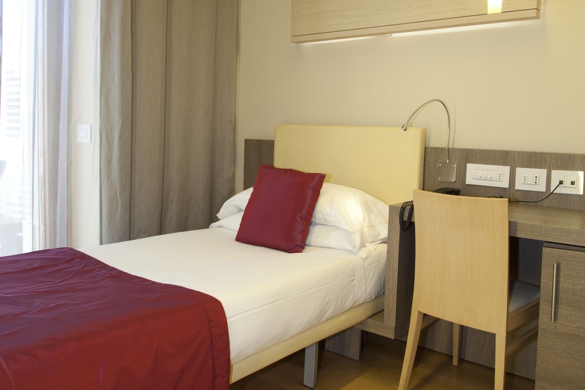 Une chambre d’hôtel avec un lit, un bureau et une chaise.