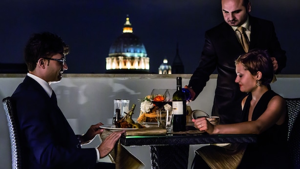 A dining table with a bottle of wine, glasses, and a plate of food.