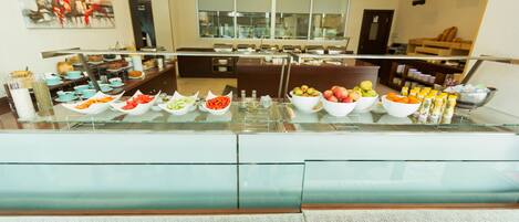 A buffet area with various food items and a seating area in the background.