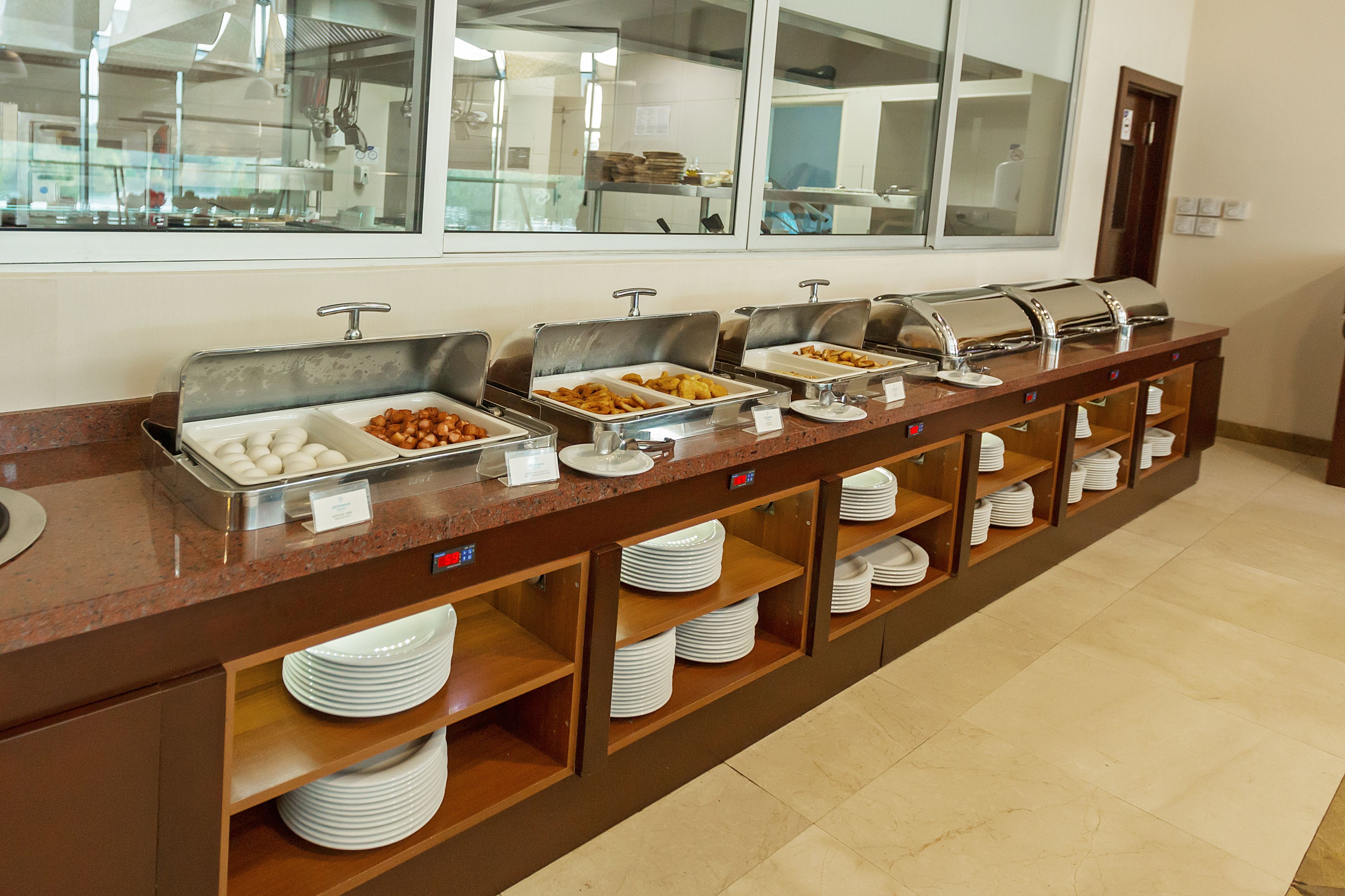 A buffet setup with multiple food stations and a counter with plates and bowls.