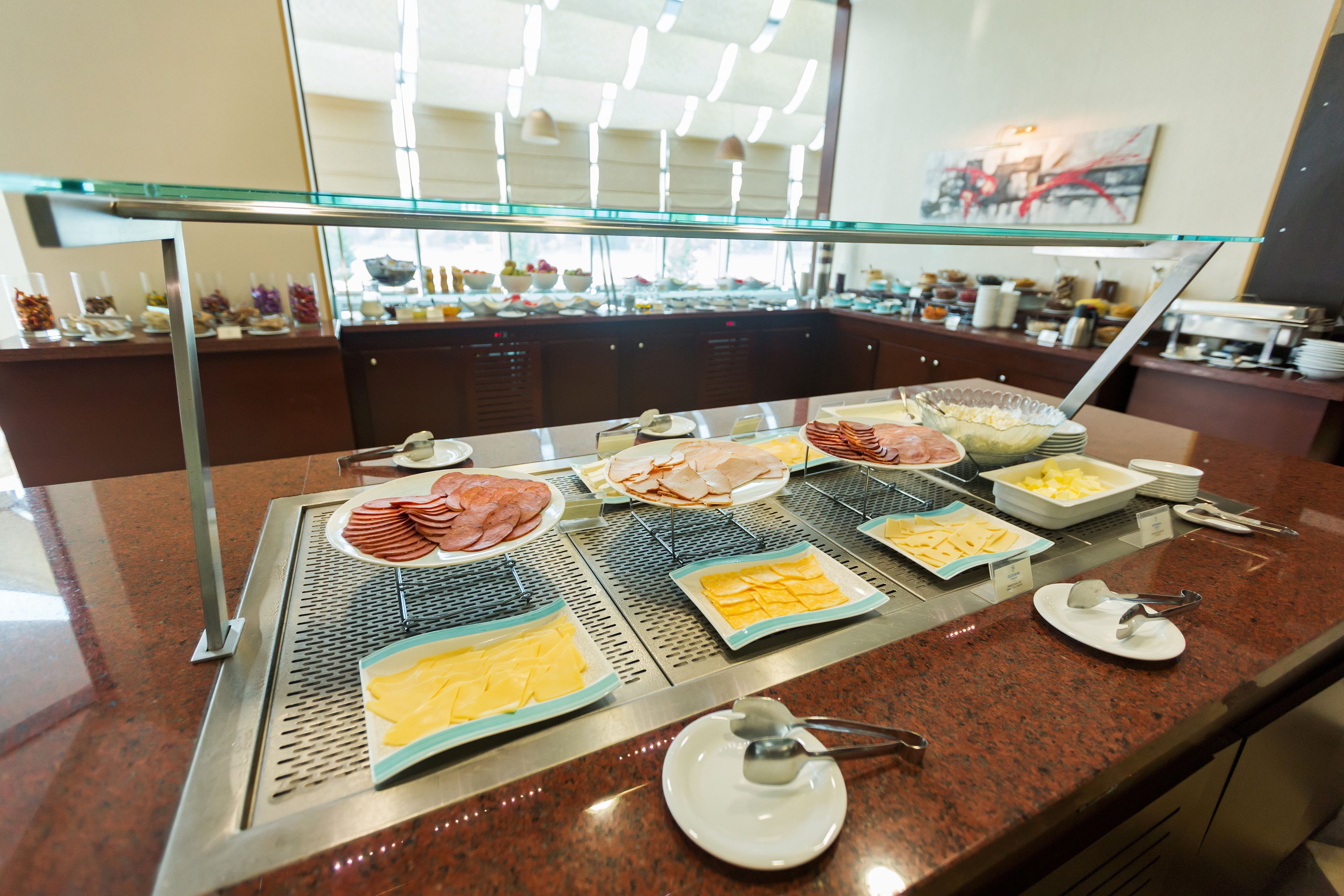 A buffet with various food items and utensils on a granite countertop.